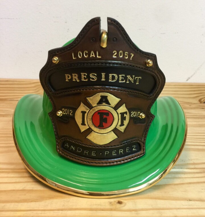 Green firefighter helmet with president badge.