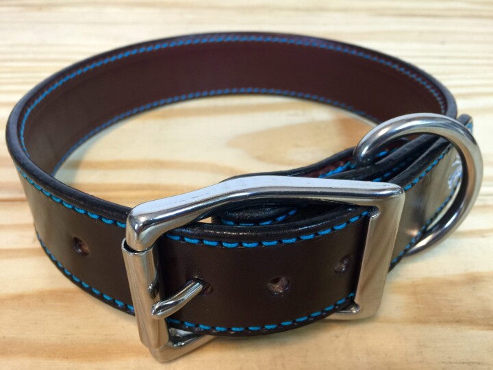 Brown leather belt with blue stitching.