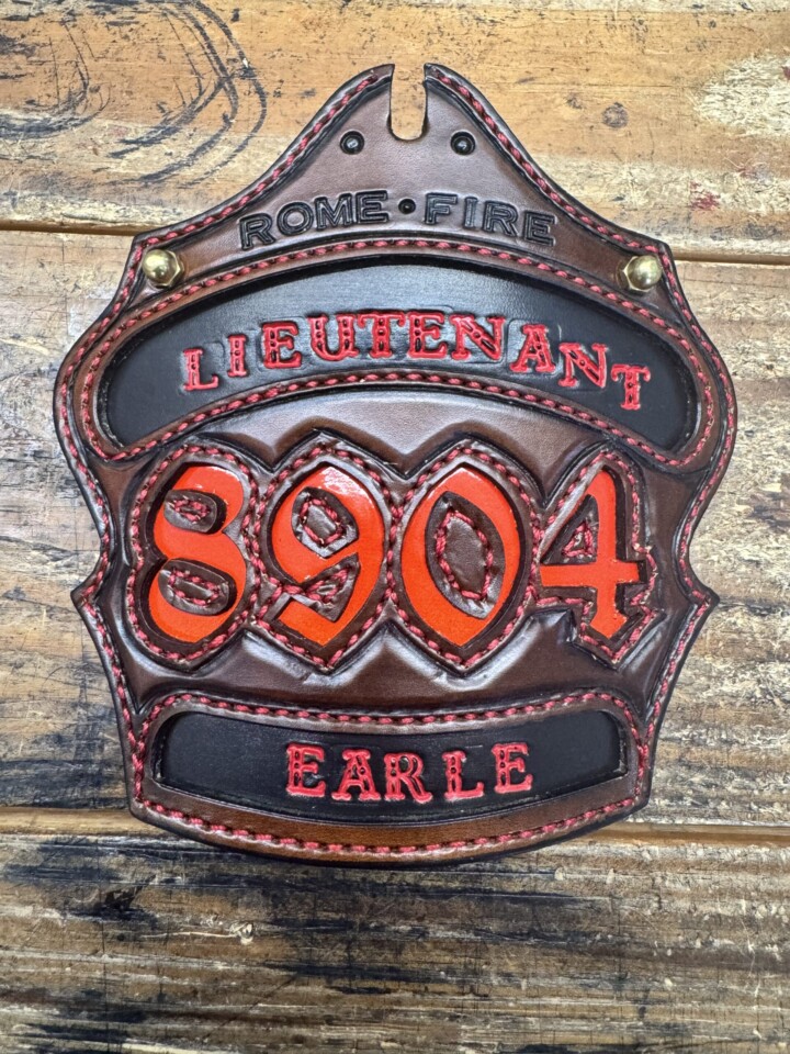 Leather fire helmet shield with red lettering.