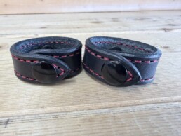 Black leather cuffs with red stitching.